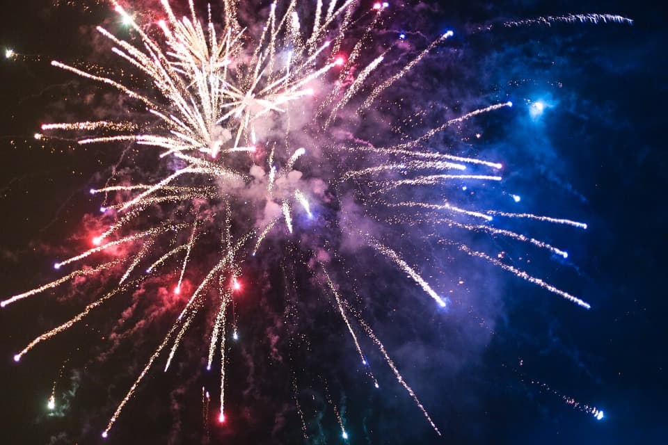 Colorful fireworks explode in the night sky.