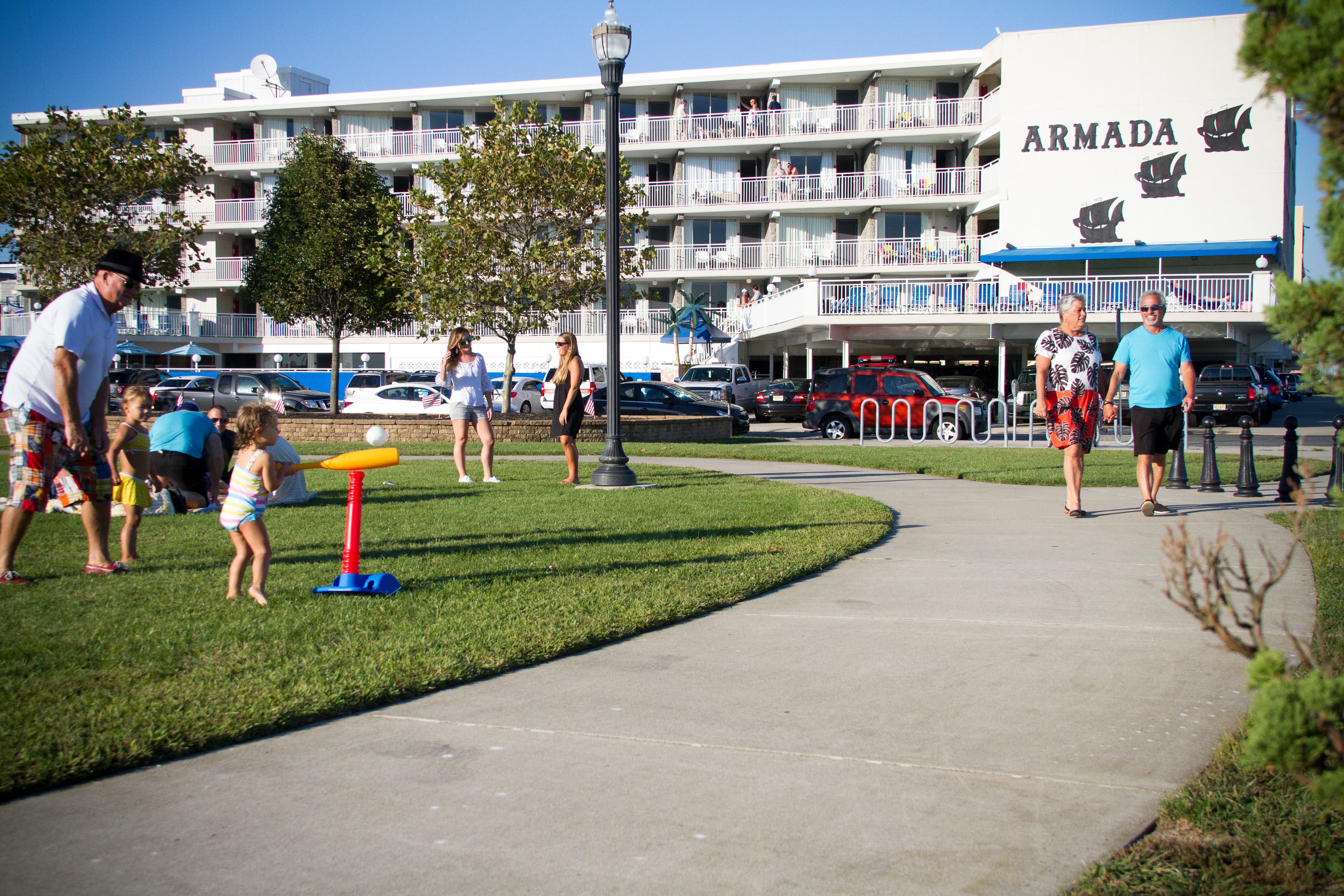 A lively park scene featuring families playing and walking near the Armada hotel.