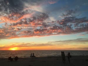 Sunset over the ocean with colorful clouds and silhouettes of people on the beach. Sunset over the ocean with colorful clouds and silhouettes of people on the beach.