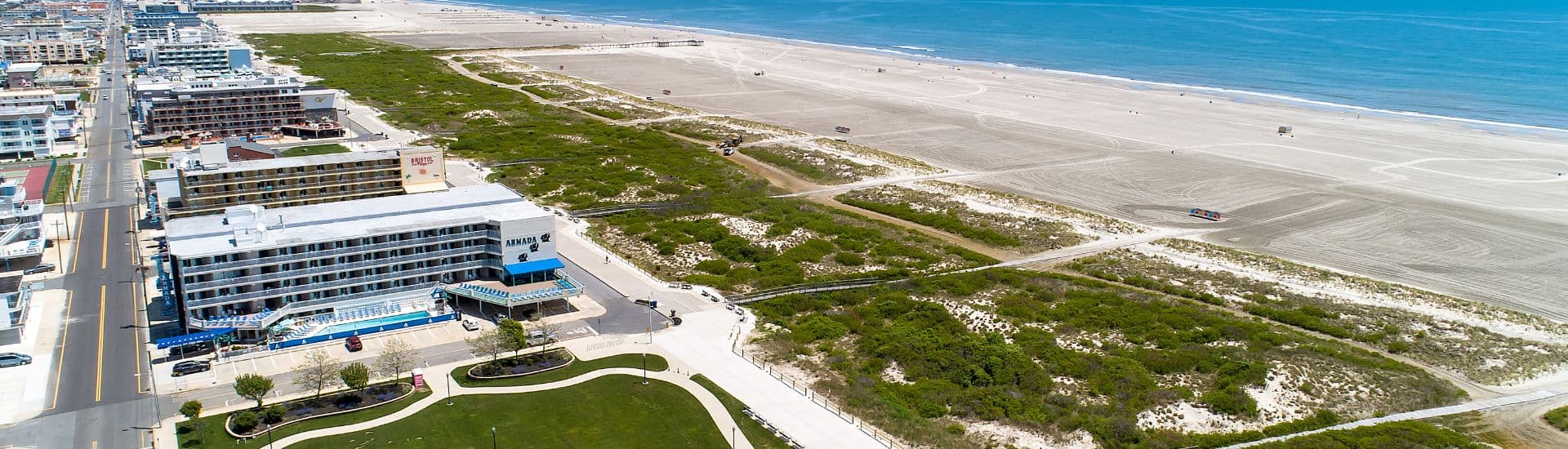 Aerial view of a beachfront hotel beside a sandy beach and ocean waves.