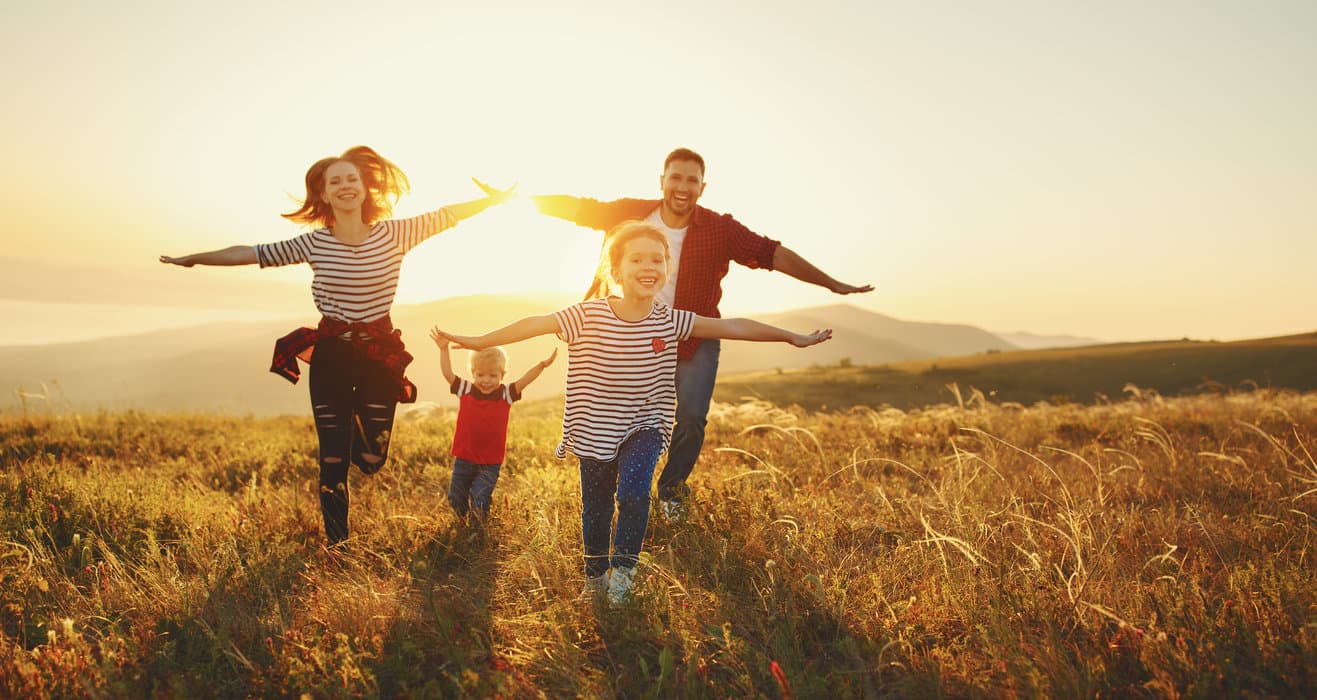 A joyful family runs together in a field at sunset. A joyful family runs together in a field at sunset.