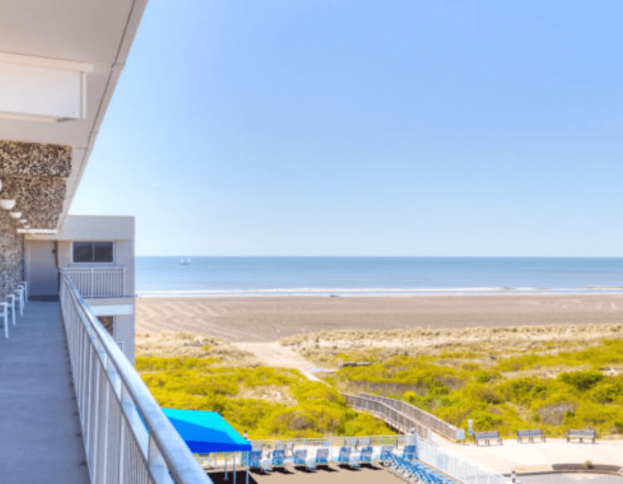 A beachside view from a balcony overlooking the ocean and sandy shore.